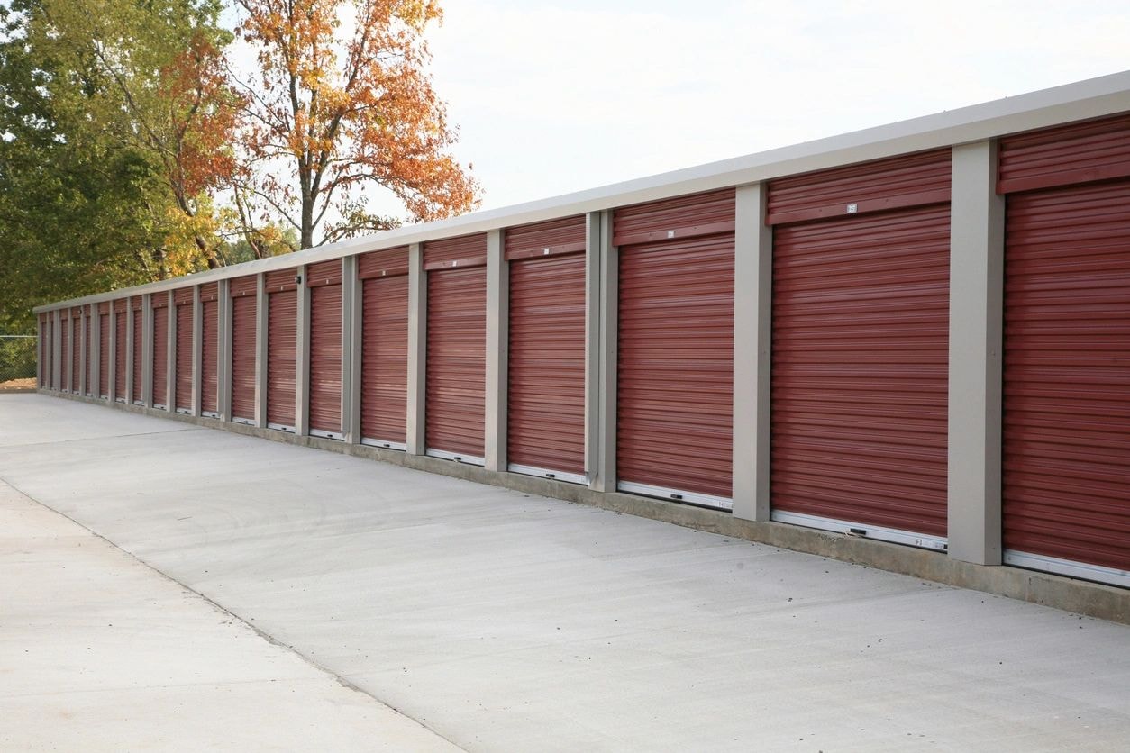Row of red self-storage unit doors with autumn trees